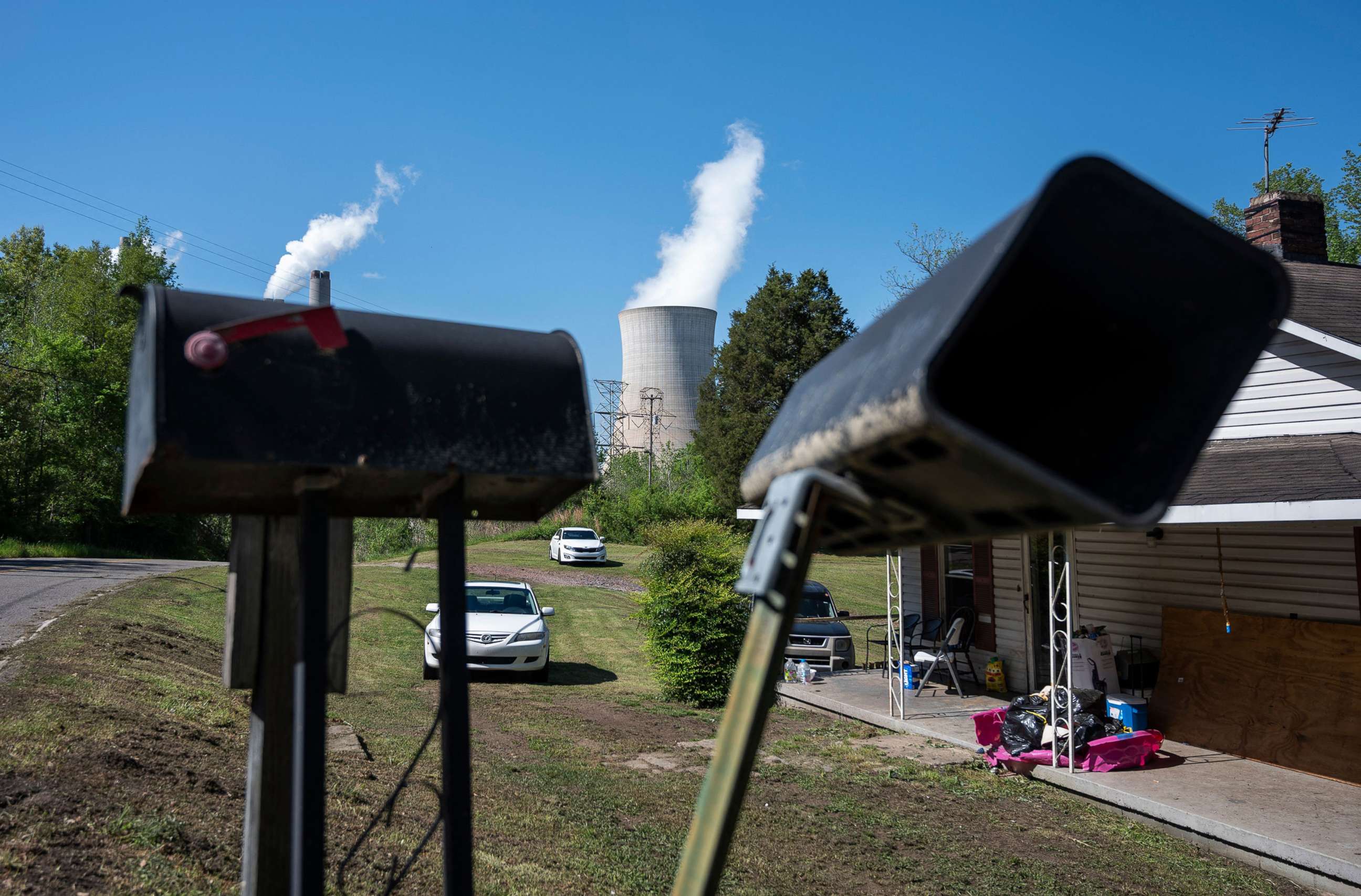 PHOTO: Cars are parked in front of a home as steam rises from the Miller coal Power Plant in Adamsville, Ala., April 11, 2021.