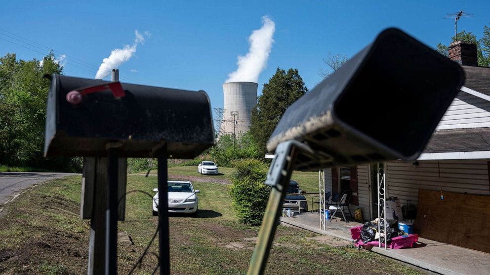 PHOTO: Cars are parked in front of a home as steam rises from the Miller coal Power Plant in Adamsville, Ala., April 11, 2021.
