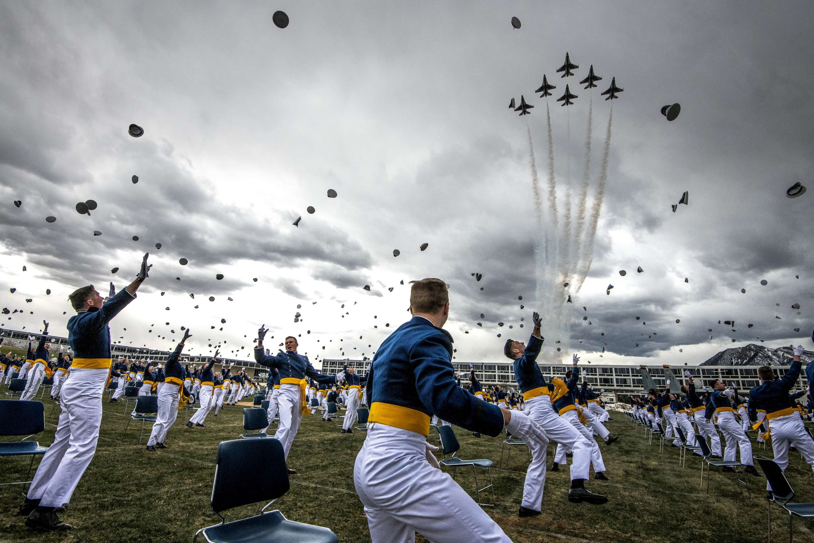 PHOTO: Spaced 8 feet apart, United States Air Force Academy cadets celebrate their graduation as a team of F-16 Air Force Thunderbirds fly over the academy on April 18, 2020 in Colorado Springs, Colo. 