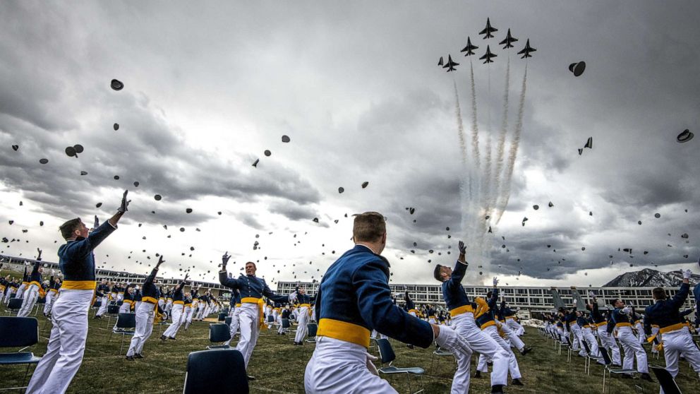 PHOTO: Spaced 8 feet apart, United States Air Force Academy cadets celebrate their graduation as a team of F-16 Air Force Thunderbirds fly over the academy on April 18, 2020 in Colorado Springs, Colo. 