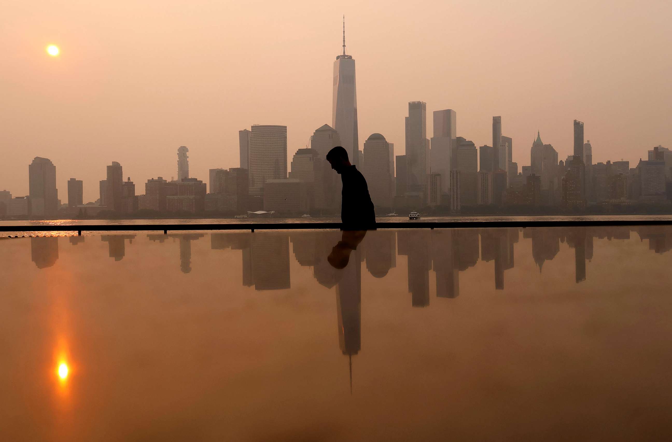 PHOTO: Smoke continues to shroud the sun as it rises behind the skyline of lower Manhattan and One World Trade Center in New York City on June 7, 2023, as seen from Jersey City, New Jersey.