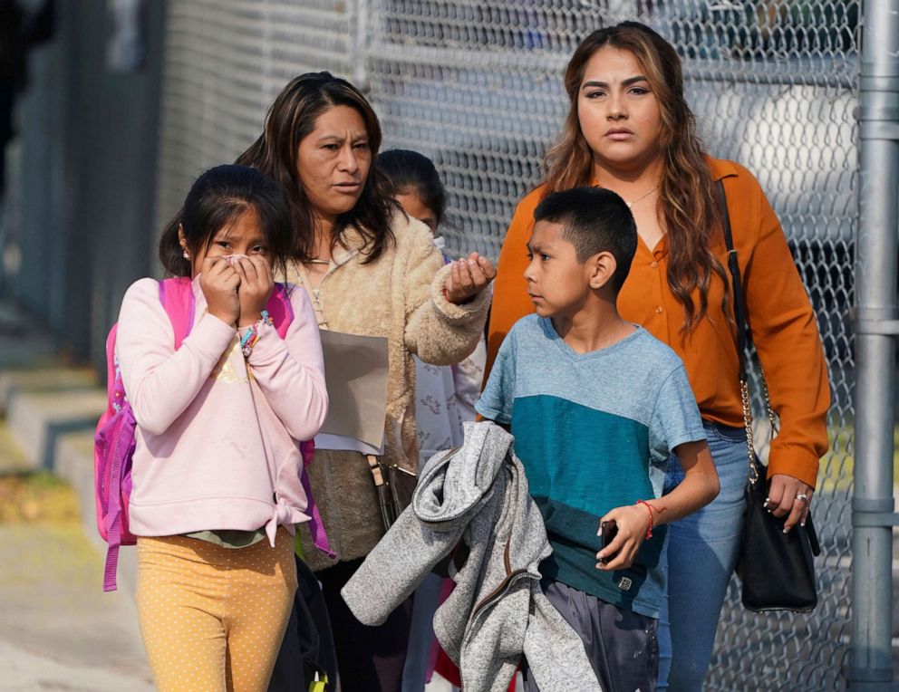 PHOTO: A girl covers her mouth and nose as parents and children leave school after jet fuel was dumped on Park Avenue Elementary School in Cudahy, Calif., Jan. 14, 2020.