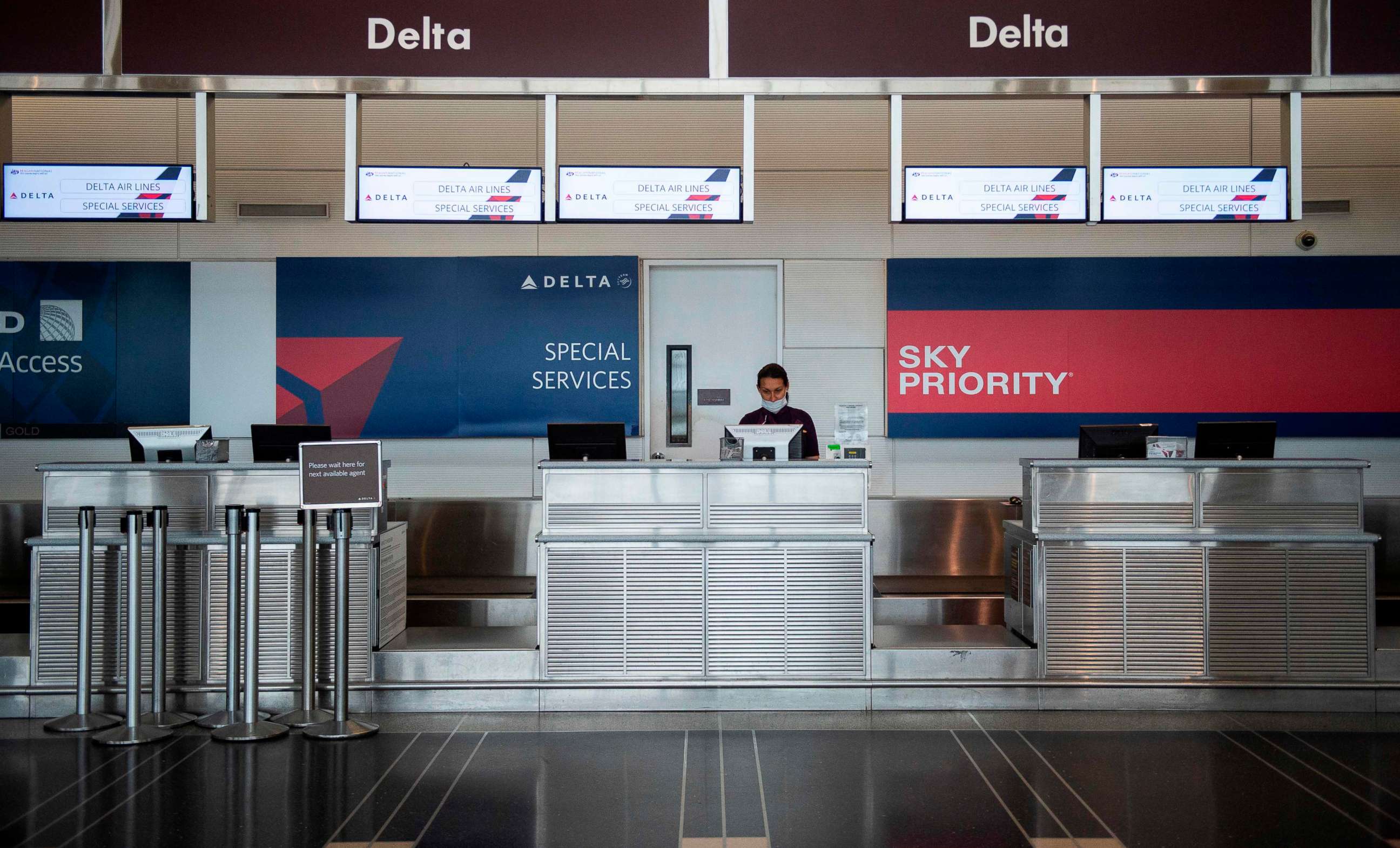 PHOTO: A Delta airlines employee waits for passengers at an empty check-in counter in Ronald Reagan Washington National Airport in Arlington, Va., May 12, 2020.