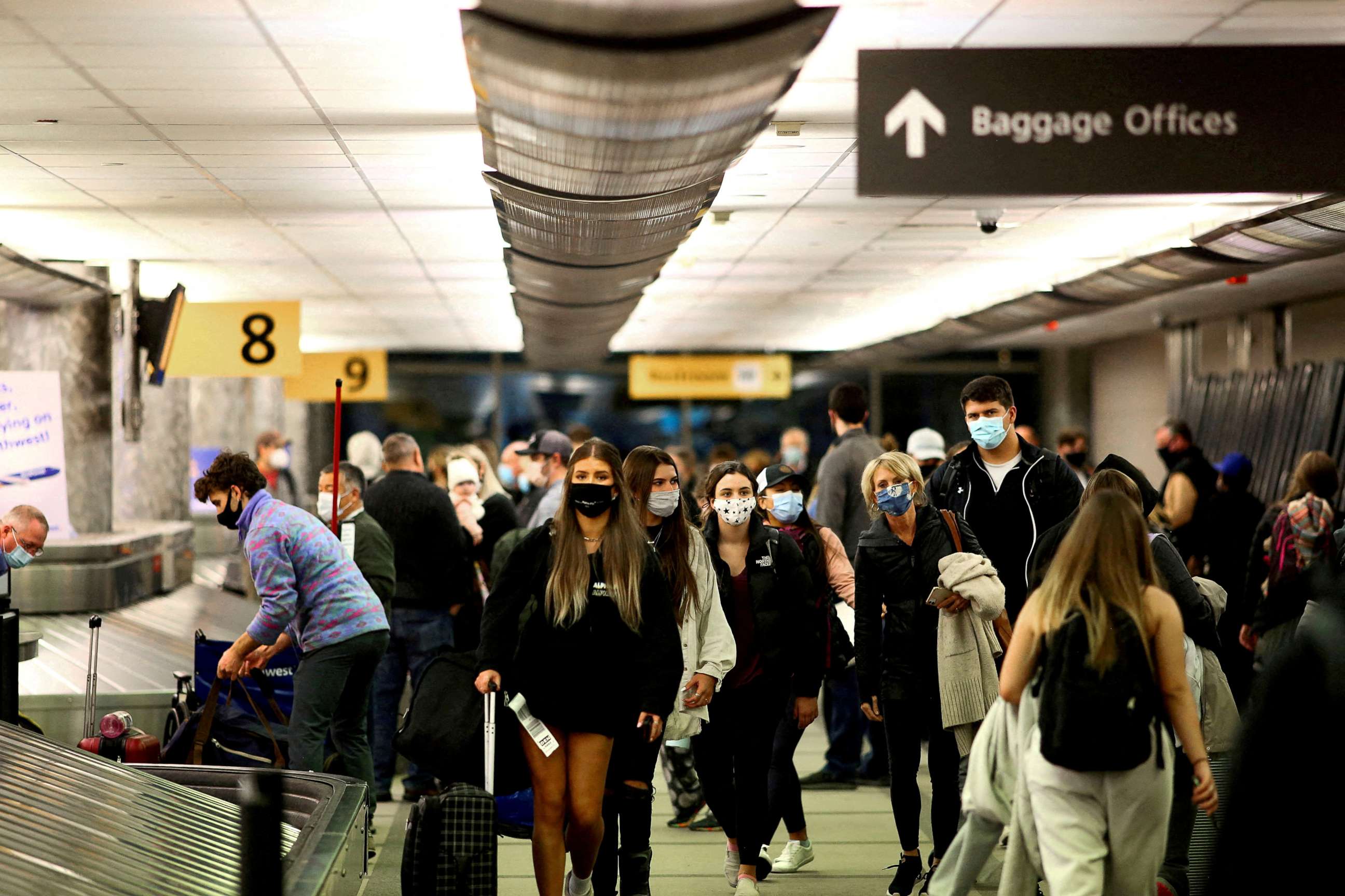 PHOTO: Travelers wearing protective face masks to prevent the spread of the coronavirus disease reclaim their luggage at the airport in Denver, Colo., Nov. 24, 2020.