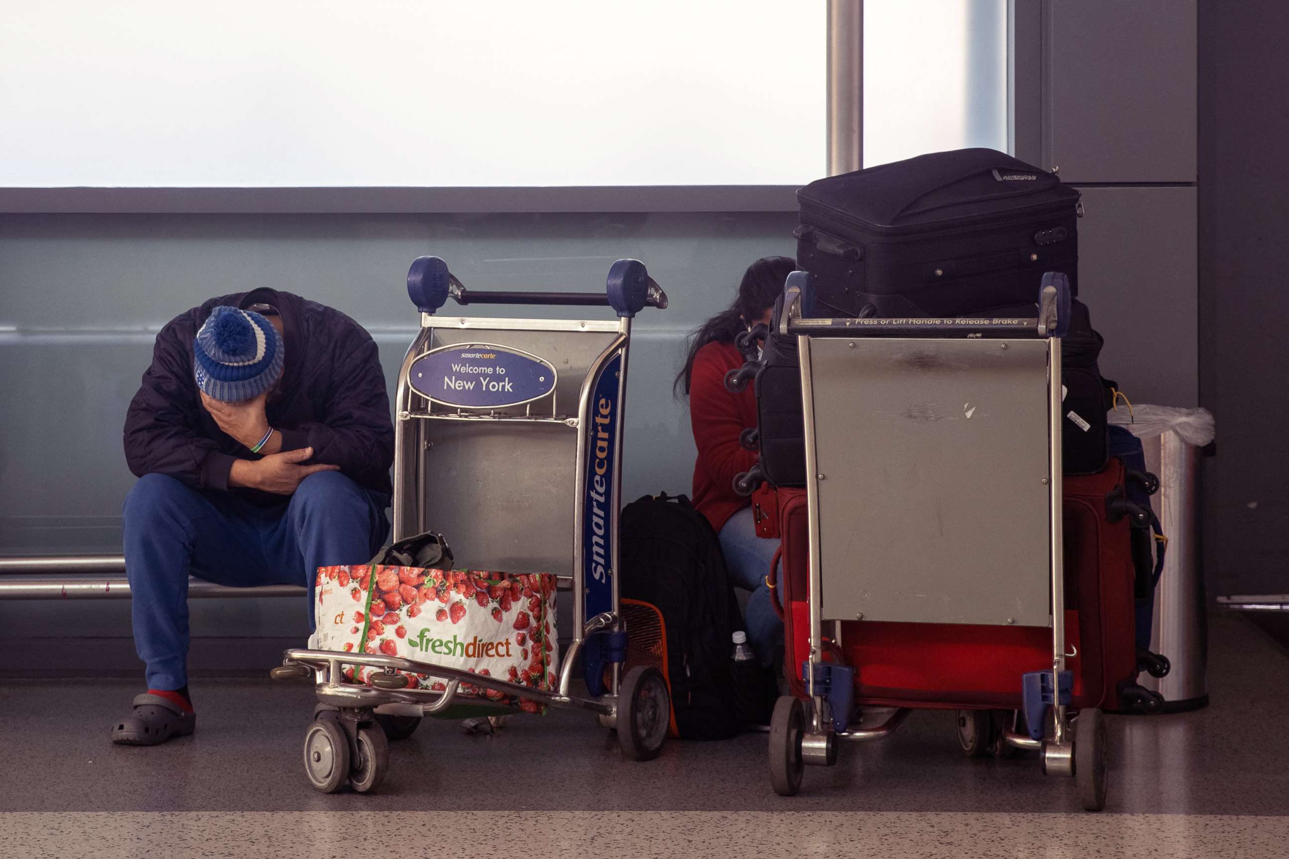 PHOTO: A passenger sits with luggage at John F. Kennedy International Airport during the spread of the Omicron coronavirus variant in Queens, New York, Dec. 26, 2021.