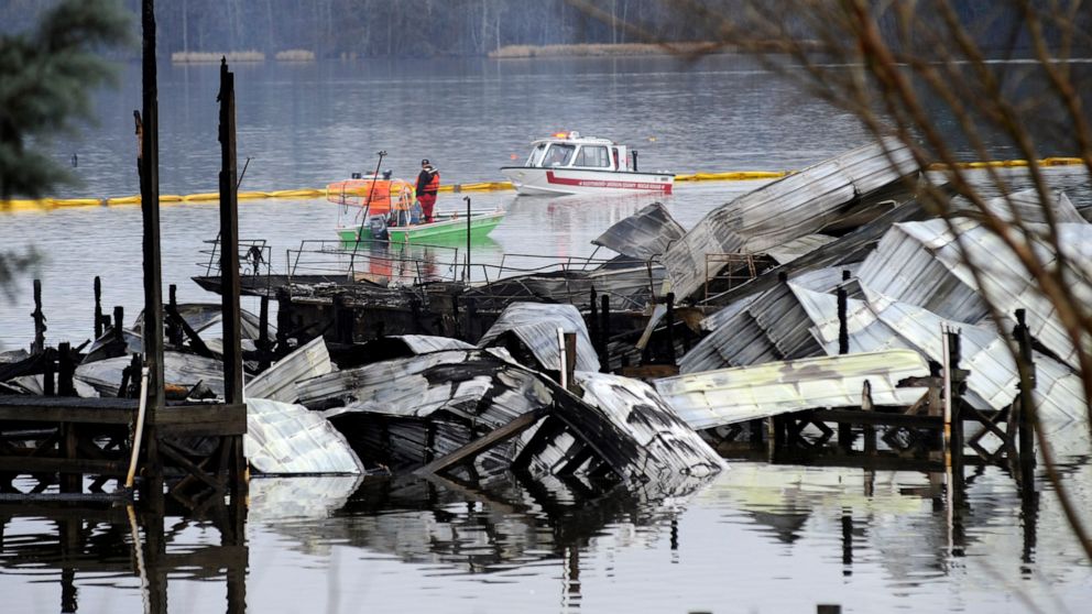 PHOTO: People on boats patrol near the charred remains of a dock following a fatal fire at a Tennessee River marina in Scottsboro, Ala., Jan. 27, 2020.