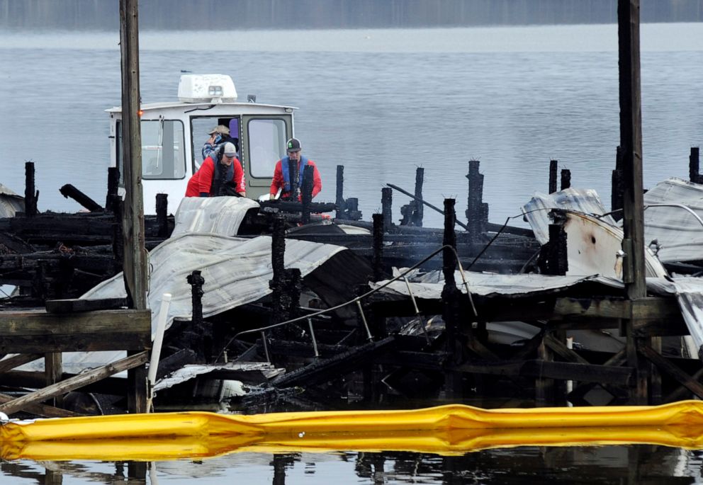 PHOTO: A crew looks at the charred remains of a boat following a fatal fire at a Tennessee River marina in Scottsboro, Ala., on Jan. 27, 2020.
