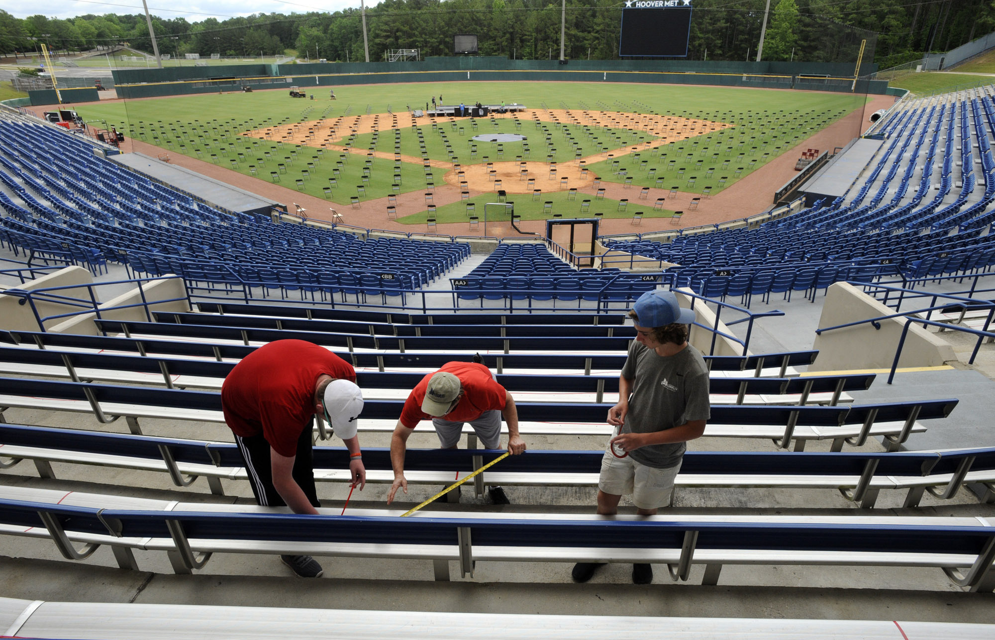 PHOTO: Workers use tape to block off seats as they prepare for a large high school graduation ceremony at Hoover Metropolitan Stadium in Hoover, Ala., Tuesday, May 19, 2020.