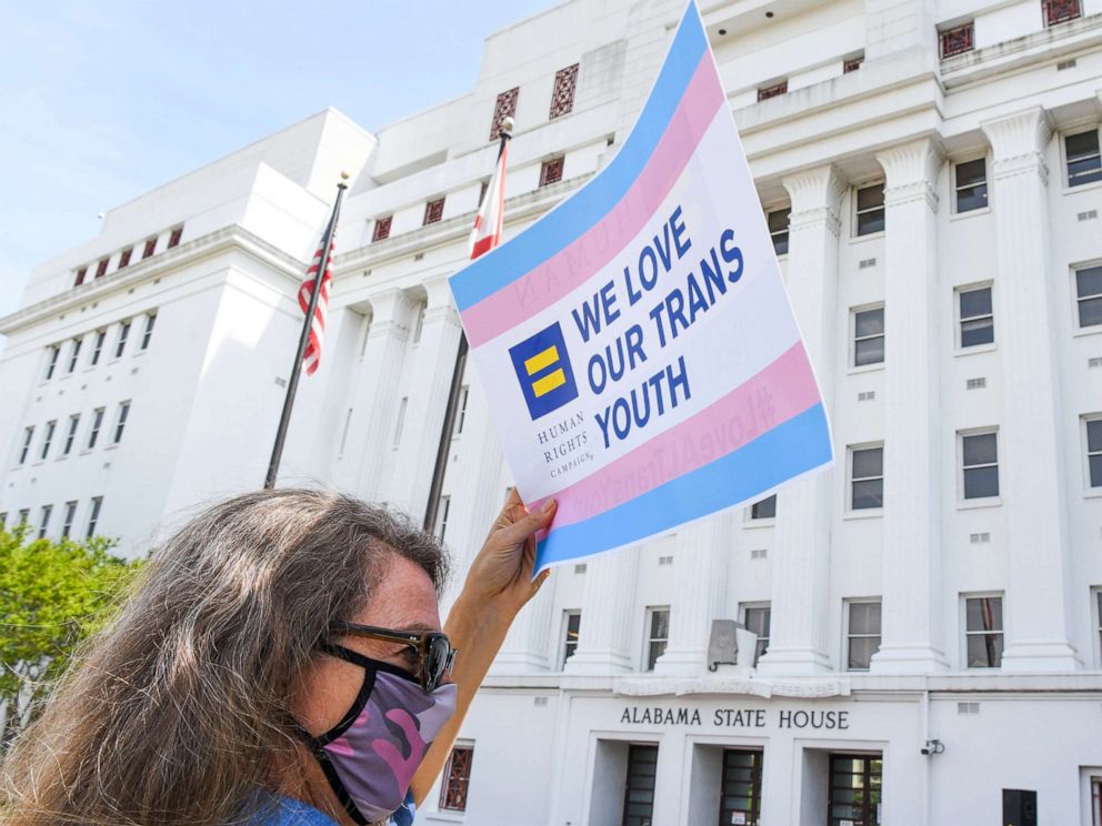 PHOTO: Jodi Womack holds a sign that reads "We Love Our Trans Youth" during a rally at the Alabama State House to draw attention to anti-transgender legislation introduced in Montgonery, Ala., March 30, 2021. 
