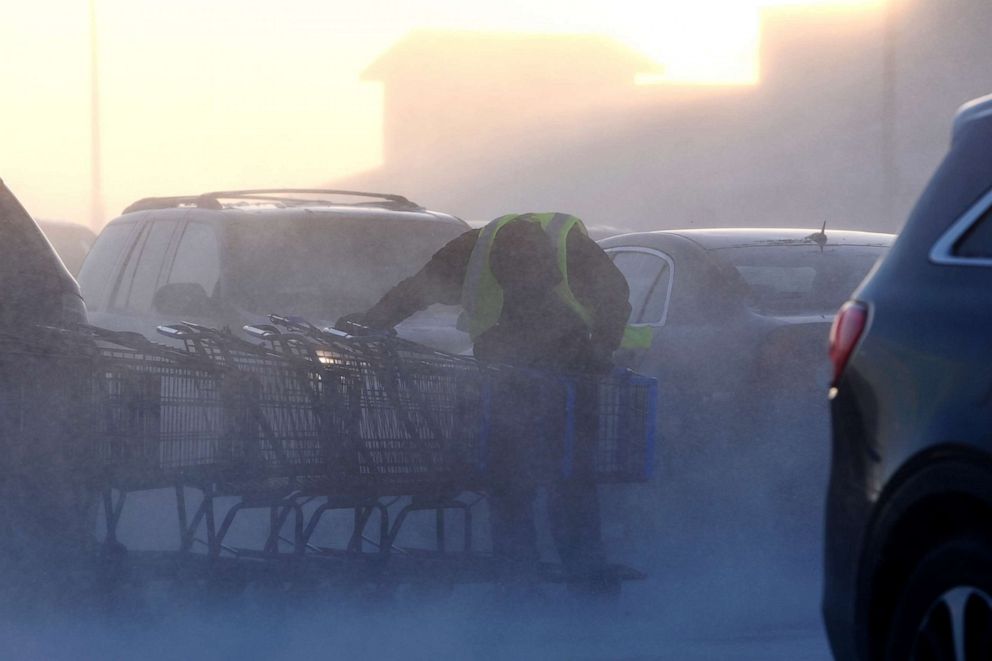 PHOTO: Kobe Anderson braces himself during a gust of wind while moving shopping carts at the Walmart Supercenter in Wasilla, Alaska, Jan. 2, 2022.