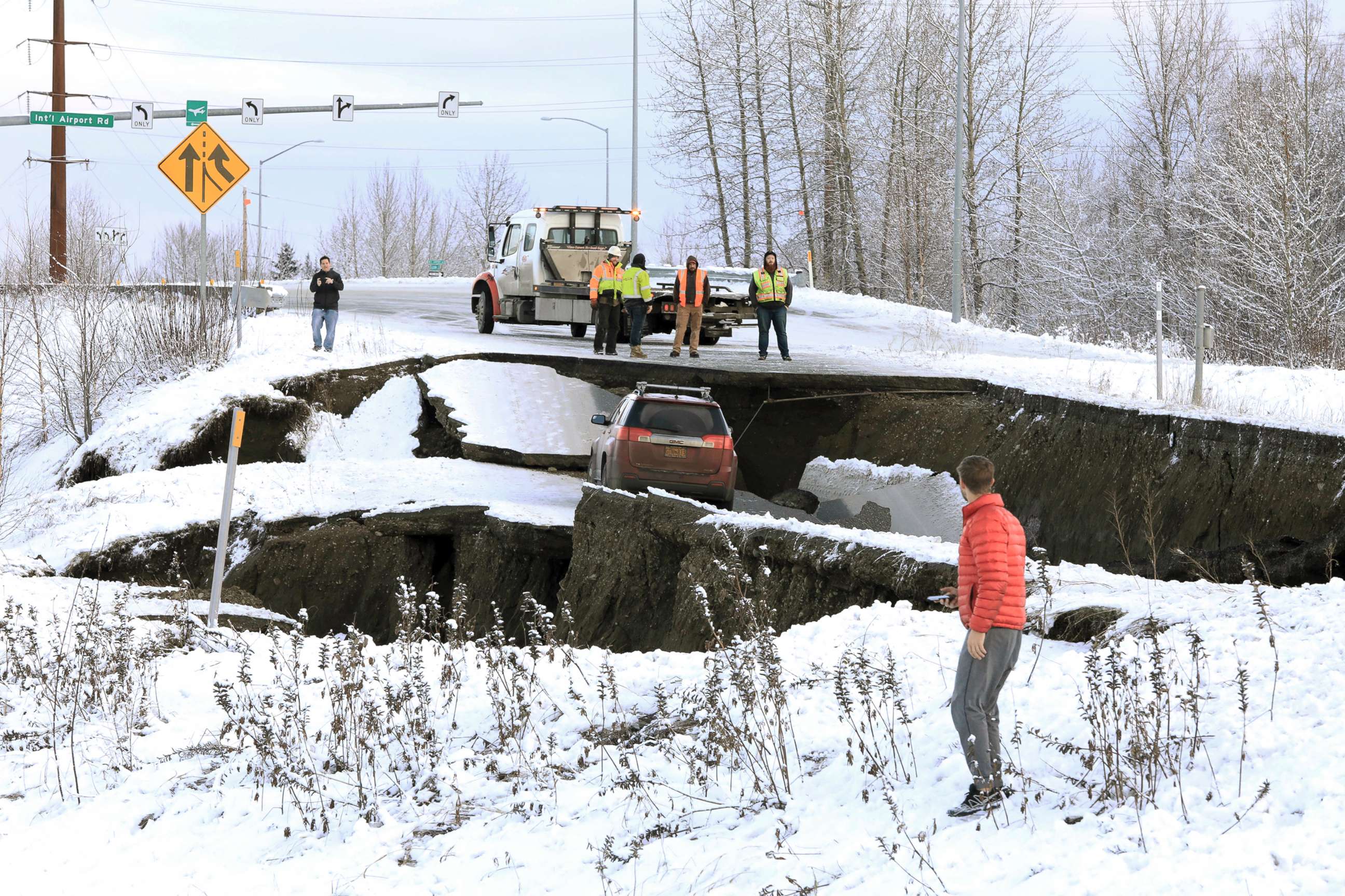 PHOTO: Highway workers and spectators look at a car stuck on a section of an off-ramp that collapsed during an earthquake in Anchorage, Ala., Nov. 30, 2018.
