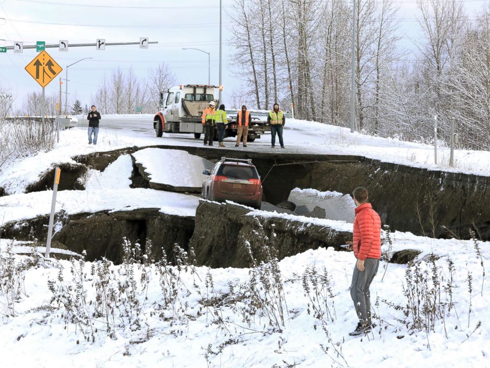 PHOTO: Highway workers and spectators look at a car stuck on a section of an off-ramp that collapsed during an earthquake in Anchorage, Ala., Nov. 30, 2018.
