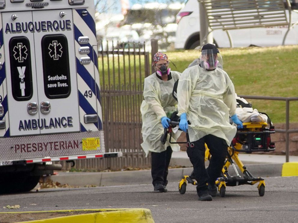 PHOTO: Albuquerque ambulance EMTs wheel a patient on a gurney in front of Presbyterian Hospital near downtown Albuquerque, N.M., Nov. 9, 2020.