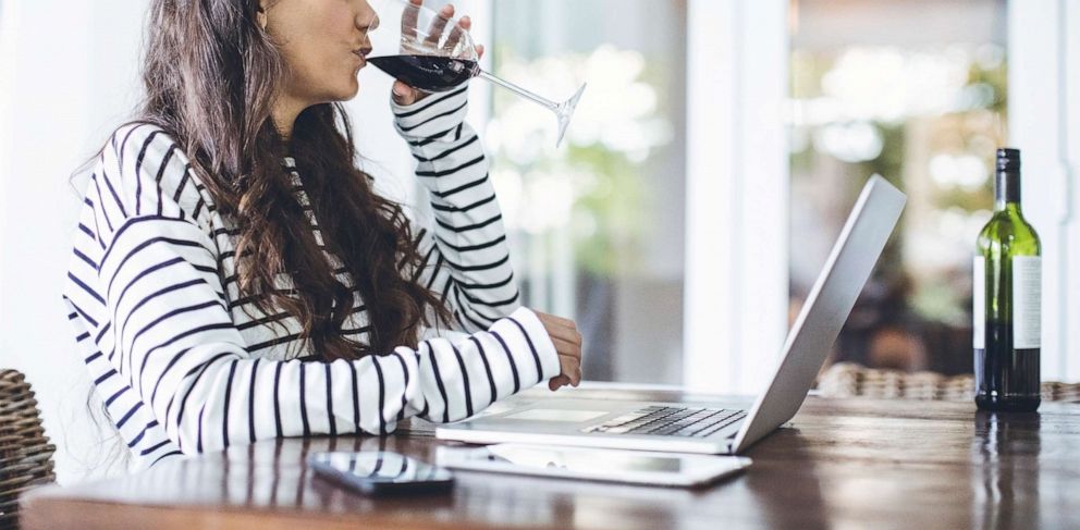 PHOTO: A woman drinks a glass of wine in front of a laptop in this stock photo.