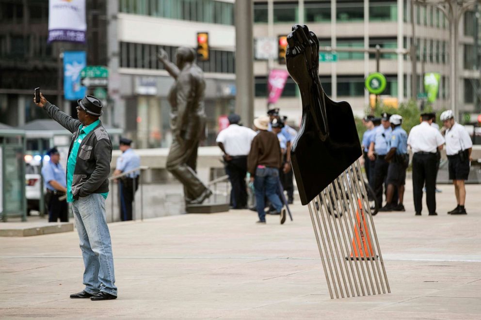 PHOTO: A man takes a selfie with Hank Willis Thomas' All Power to All People sculpture in view of a statue of former Philadelphia mayor and police commissioner Frank Rizzo in Philadelphia, Sept. 14, 2017.
