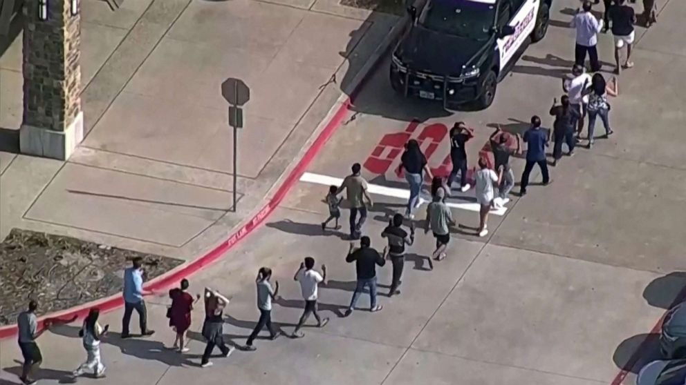 PHOTO: Shoppers leave with hands up as law enforcement responds to a shooting in the Dallas area's Allen Premium Outlets, which authorities said has left multiple people injured in Allen, Texas, May 6, 2023.