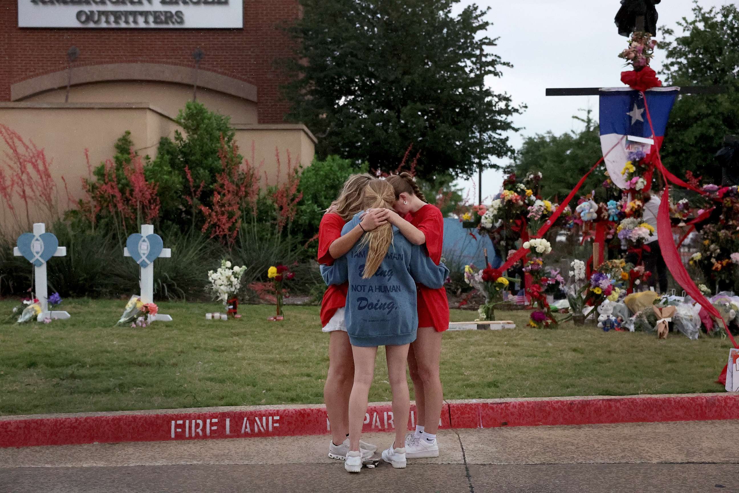 PHOTO: People pray near a makeshift memorial setup near an entrance to the Allen Premium Outlets mall following the mass shooting, May 8, 2023 in Allen, Texas.