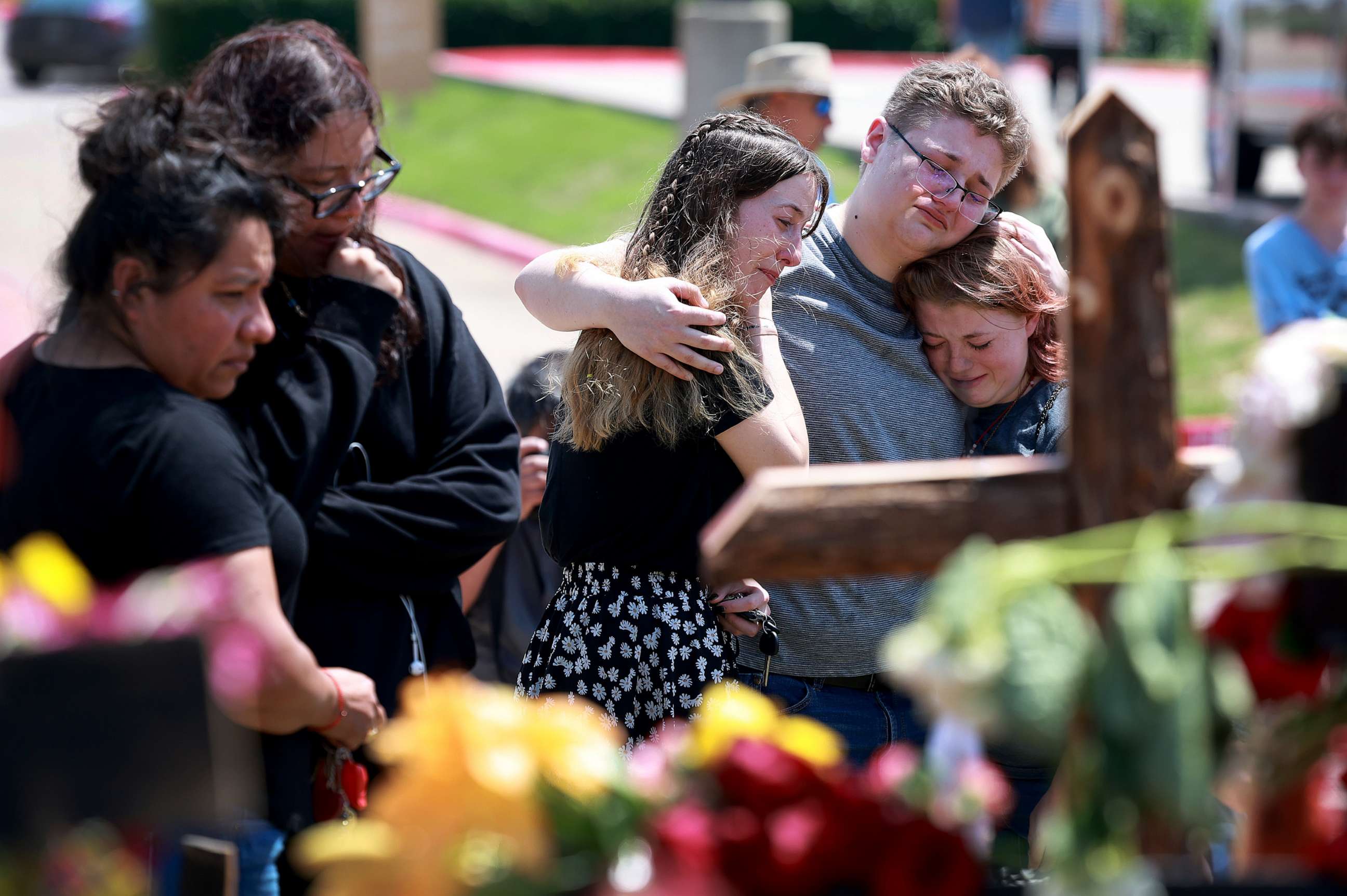 PHOTO: Jenni Seeley, Dakota Britvich, and Abbi Boyd hug as they visit a memorial set up near the scene of a mass shooting at the Allen Premium Outlets mall on May 8, 2023 in Allen, Texas.