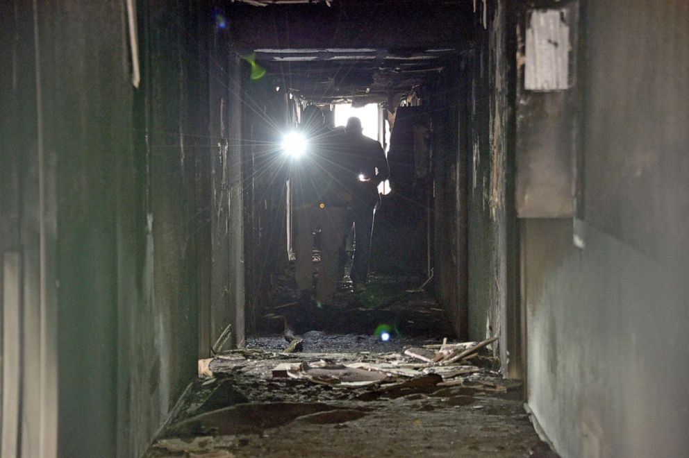 PHOTO: Investigators walk through an interior corridor after a fire at a three-story apartment complex, Dec. 21, 2019 in Las Vegas.