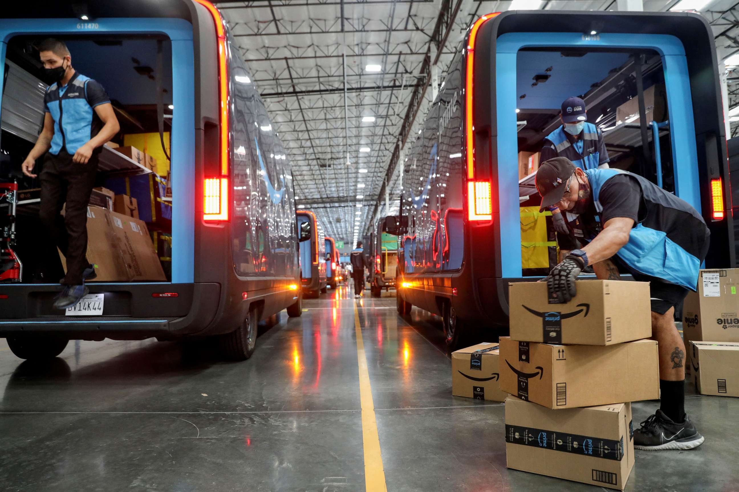 PHOTO: Workers load packages into Amazon Rivian electric trucks at an Amazon facility in Poway, California, U.S., November 16, 2022.