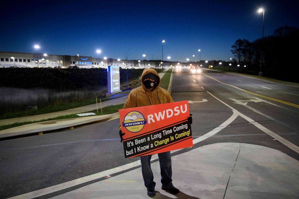 PHOTO: A union supporter stands before sunrise outside the Amazon.com, Inc. BHM1 fulfillment center in Bessemer, Alabama, March 29, 2021.