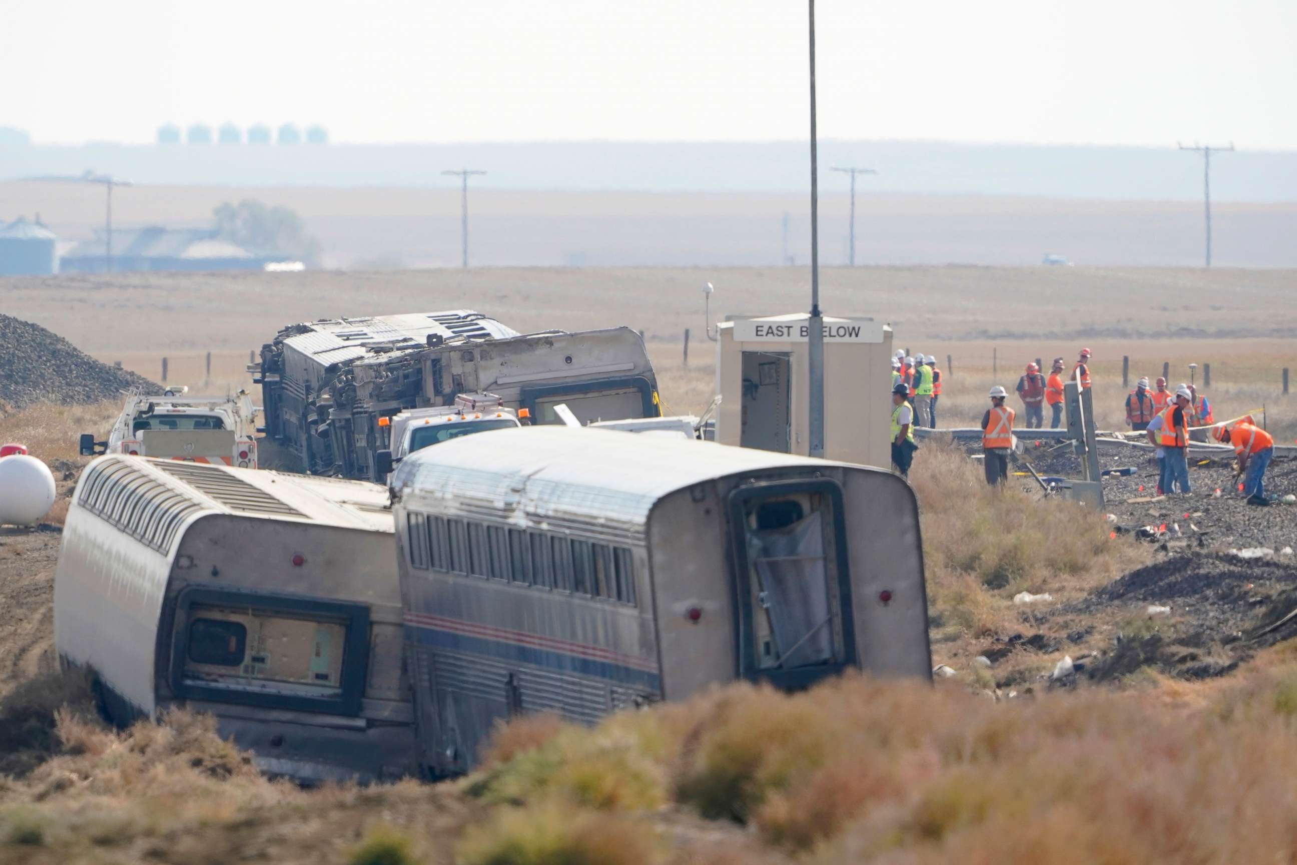 PHOTO: Workers stand near train tracks, Sept. 27, 2021, next to overturned cars from an Amtrak train that derailed Sept. 25, near Joplin, Mont., killing three people and injuring others.