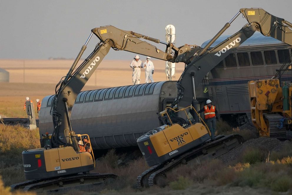 PHOTO: Workers stand on a toppled train car as front-loaders prop up another, Sept. 26, 2021, from an Amtrak train that derailed the day before, just west of Joplin, Mont.