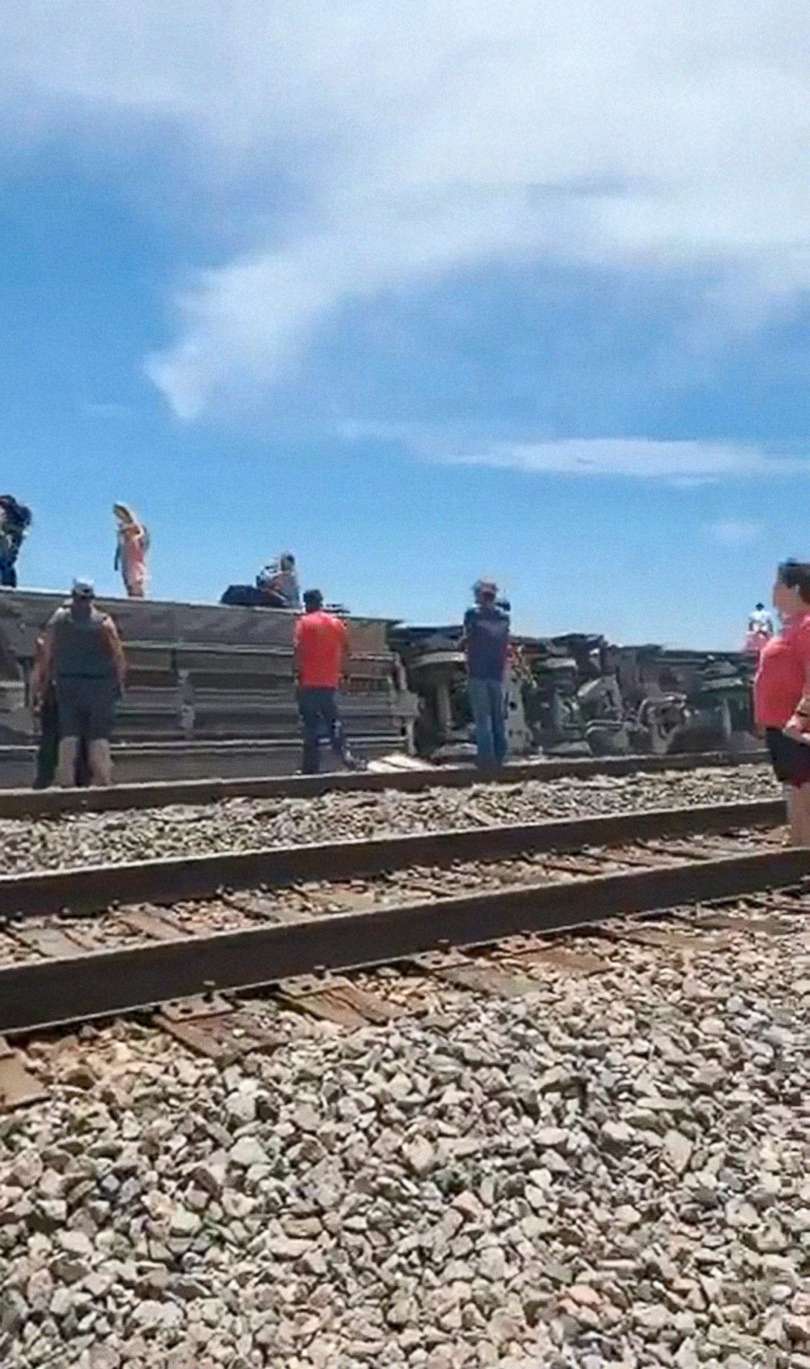 PHOTO: Passengers stand around several cars of an Amtrak train that derailed after hitting a dump truck at a public crossing in Mendon, Mo., June 27, 2022.