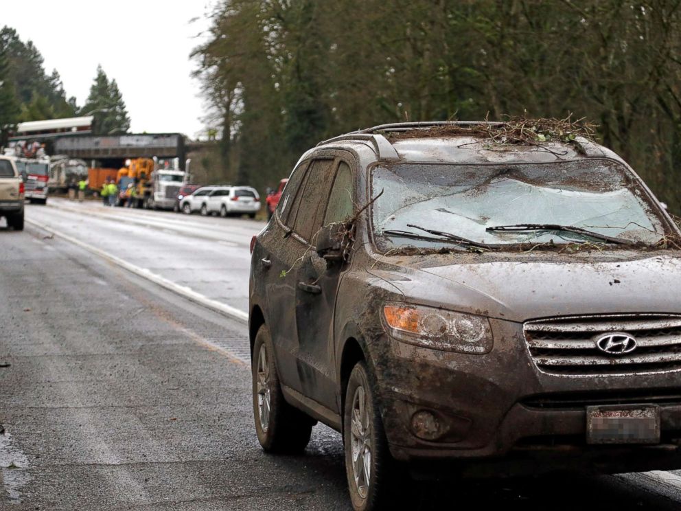 PHOTO: A car covered in mud and debris with a smashed windshield and other damage sits parked on the shoulder just beyond where an Amtrak train derailed onto Interstate 5, Dec. 18, 2017, in DuPont, Wash.