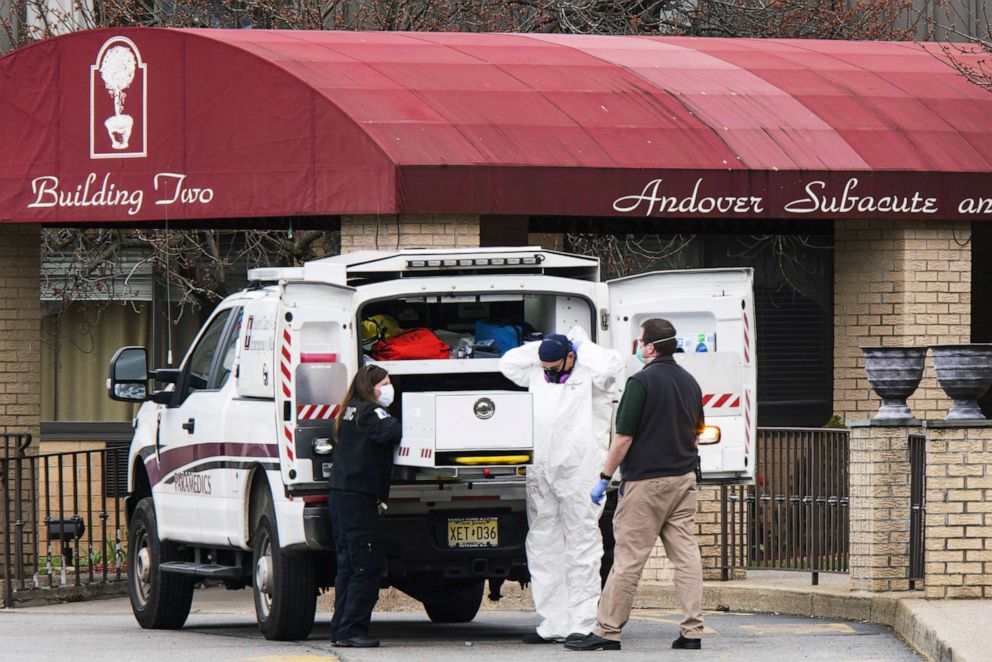 PHOTO: Medical workers put on masks and personal protective equipment (PPE) while preparing to transport a deceased body at Andover Subacute and Rehabilitation Center on April 16, 2020 in Andover, N.J. 