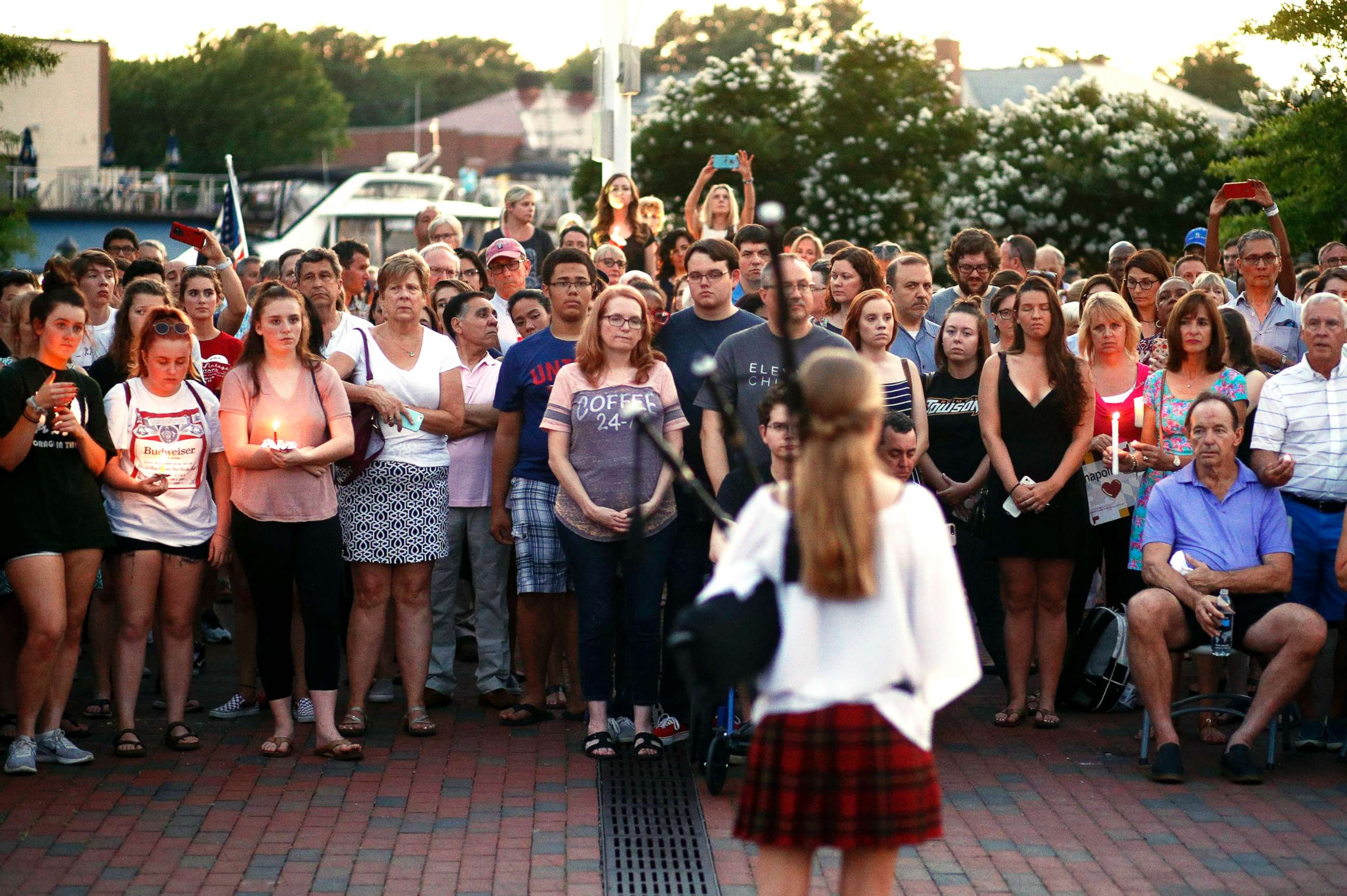 PHOTO: People listen to a bagpipe player during a vigil in response to a shooting in the Capital Gazette newspaper office on June 29, 2018, in Annapolis, Md.