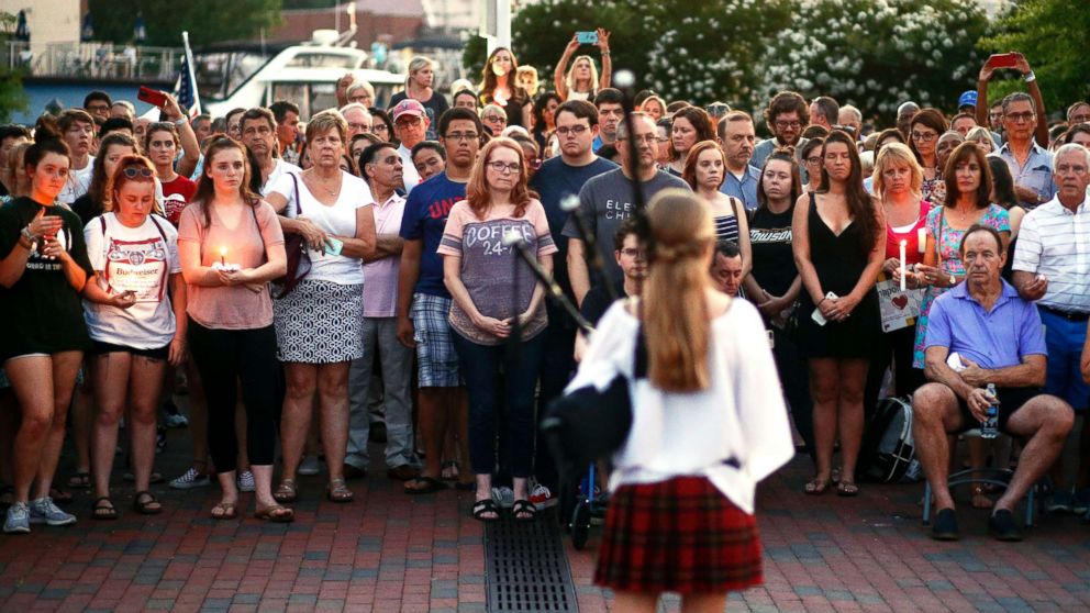 People listen to a bagpipe player during a vigil in response to a shooting in the Capital Gazette newspaper office on June 29, 2018, in Annapolis, Md.