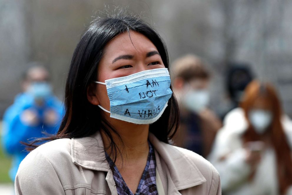 PHOTO: A demonstrator wearing a mask saying "I am not a virus" listens to a speech at a rally against Asian hate crimes, Saturday, March 27, 2021, at Chicago's Grant Park. 