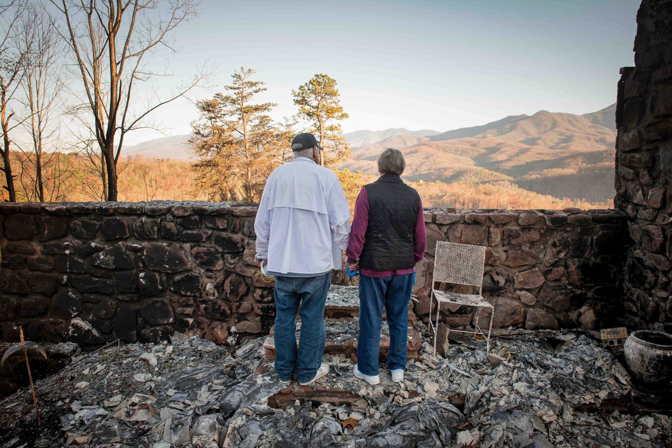 PHOTO: Richard T. Ramsey and Sue Ramsey hold hands while looking at the skyline from the remains of their house of 41 years, Dec. 1, 2016, in Gatlinburg, Tennessee. 
