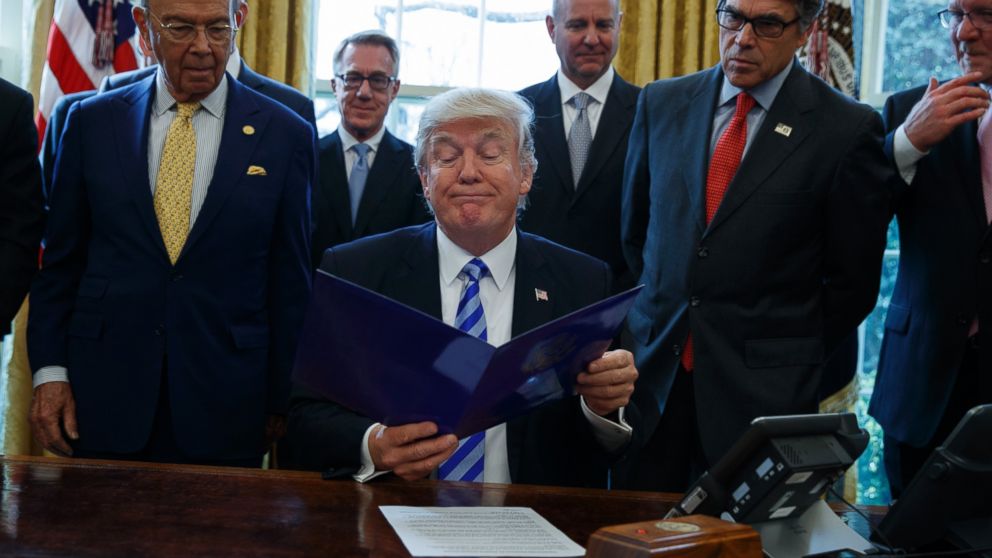President Donald Trump, flanked by Commerce Secretary Wilbur Ross and Energy Secretary Rick Perry, is seen in the Oval Office of the White House in Washington, March 24, 2107, where he announced the approval of a permit to build the Keystone XL pipeline.