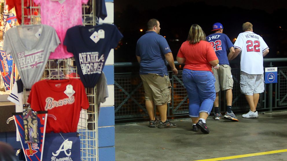 Baseball fans look over  a railing at Turner Field near the scene where a man fell 60 feet from the upper deck Monday Aug. 12, 2013.  Atlanta police spokesman John Chafee confirmed the death of the man, whose name has not been released. 