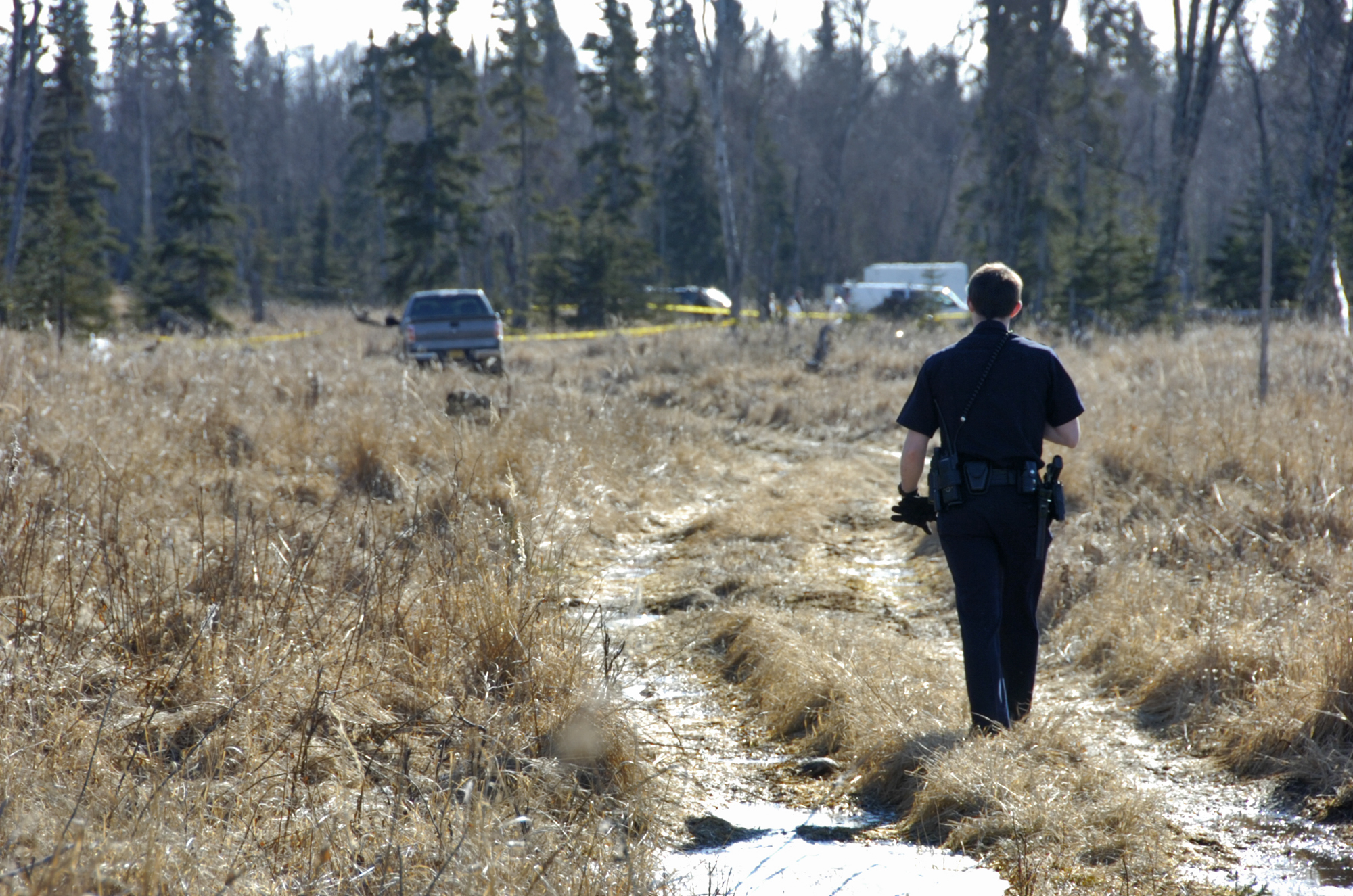 PHOTO: On March 22, 2015, a Kenai police officer walks down a trail leading to a temporary camp where police and Federal Bureau of Investigations personnel are working to identify human remains.