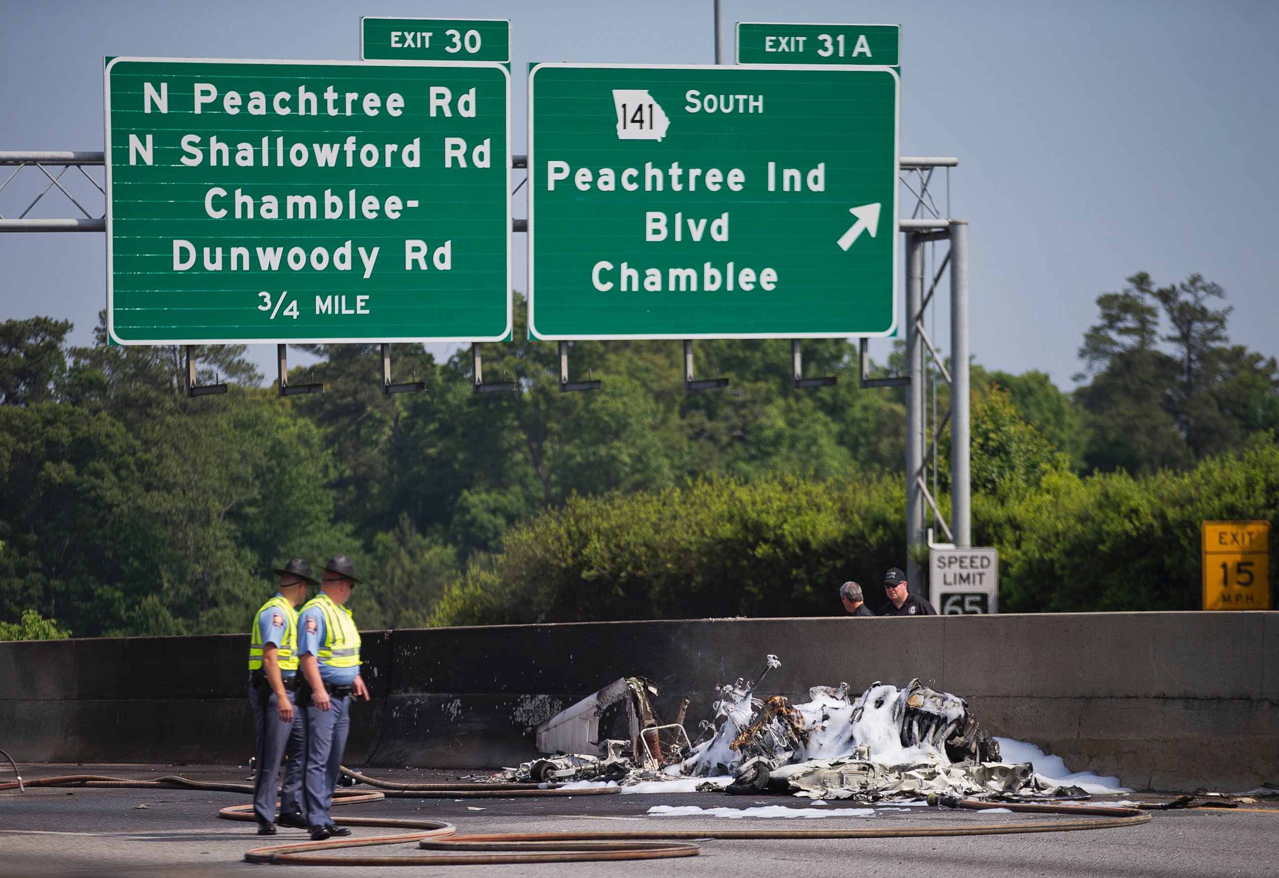 PHOTO: Police look toward the wreckage of a plane crash on Interstate 285, Friday, May 8, 2015, in Doraville, Ga.  Spokesman Capt. Eric Jackson of the DeKalb County Fire Department told reporters that four were onboard, and all died. 