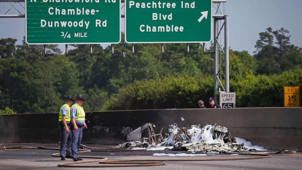 PHOTO: Police look toward the wreckage of a plane crash on Interstate 285, Friday, May 8, 2015, in Doraville, Ga.  Spokesman Capt. Eric Jackson of the DeKalb County Fire Department told reporters that four were onboard, and all died. 