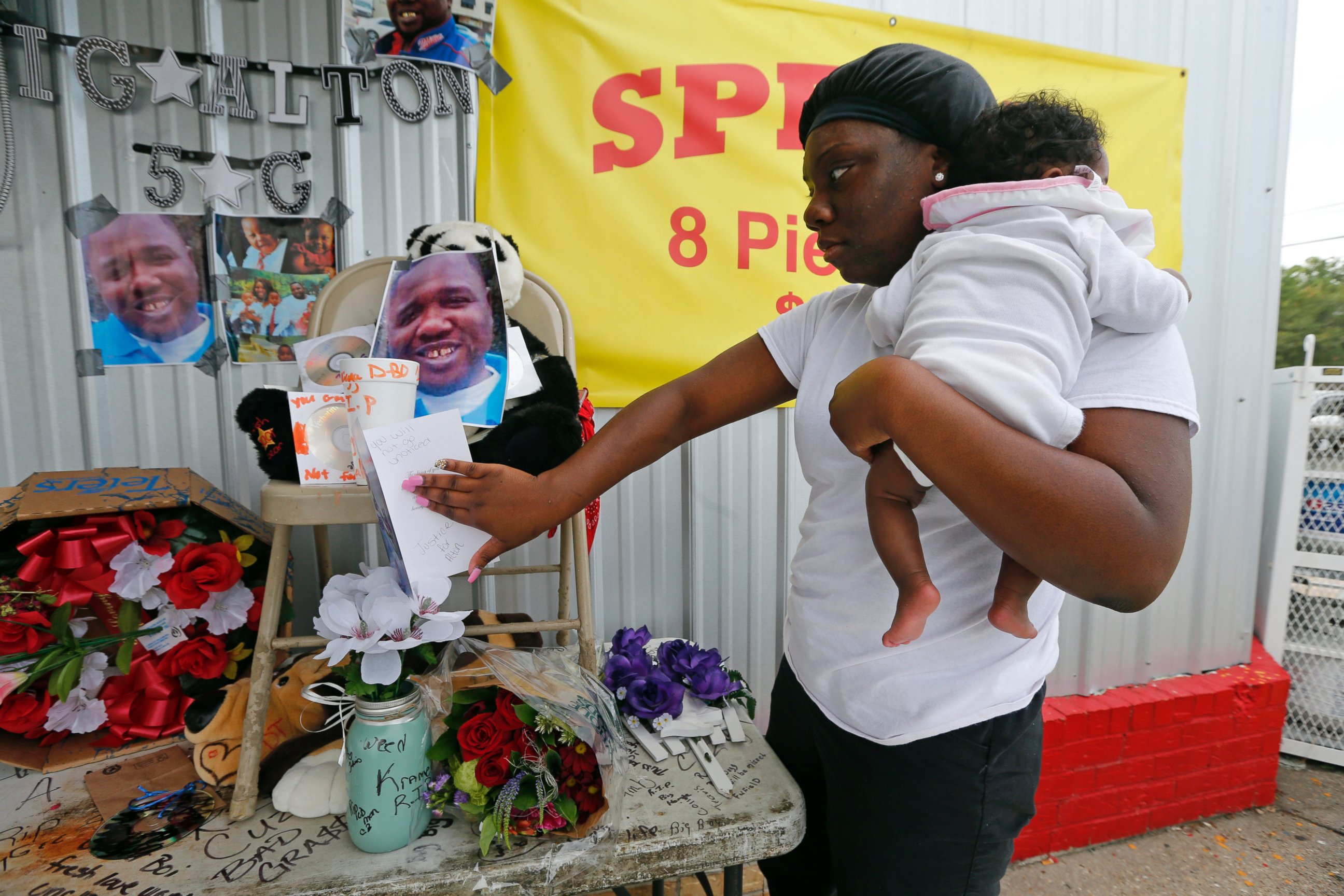PHOTO: Shermire Reed, holding her daughter Zoe, places a card at a makeshift memorial outside a convenience store in Baton Rouge, Louisiana, July 6, 2016.