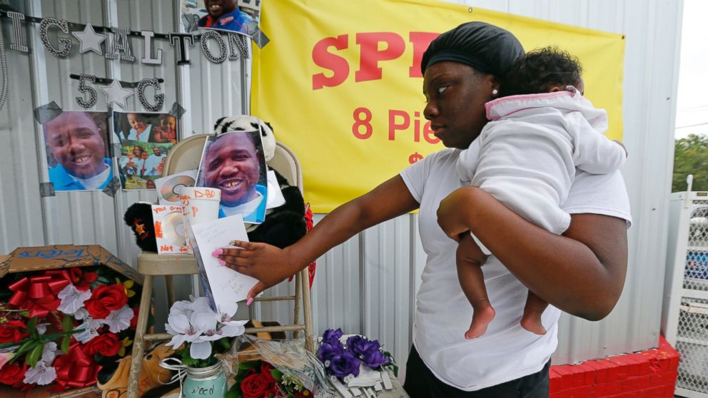 PHOTO: Shermire Reed, holding her daughter Zoe, places a card at a makeshift memorial outside a convenience store in Baton Rouge, Louisiana, July 6, 2016.