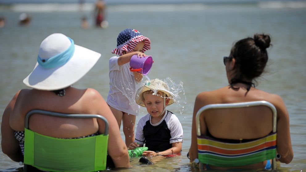Lauren Rhyner, 1, dumps a bucket of water on her 4-year-old brother Jackson Rhyner's head while the family cools off in a shallow tidal pool, Aug. 23, 2014, on Tybee Island, Ga.