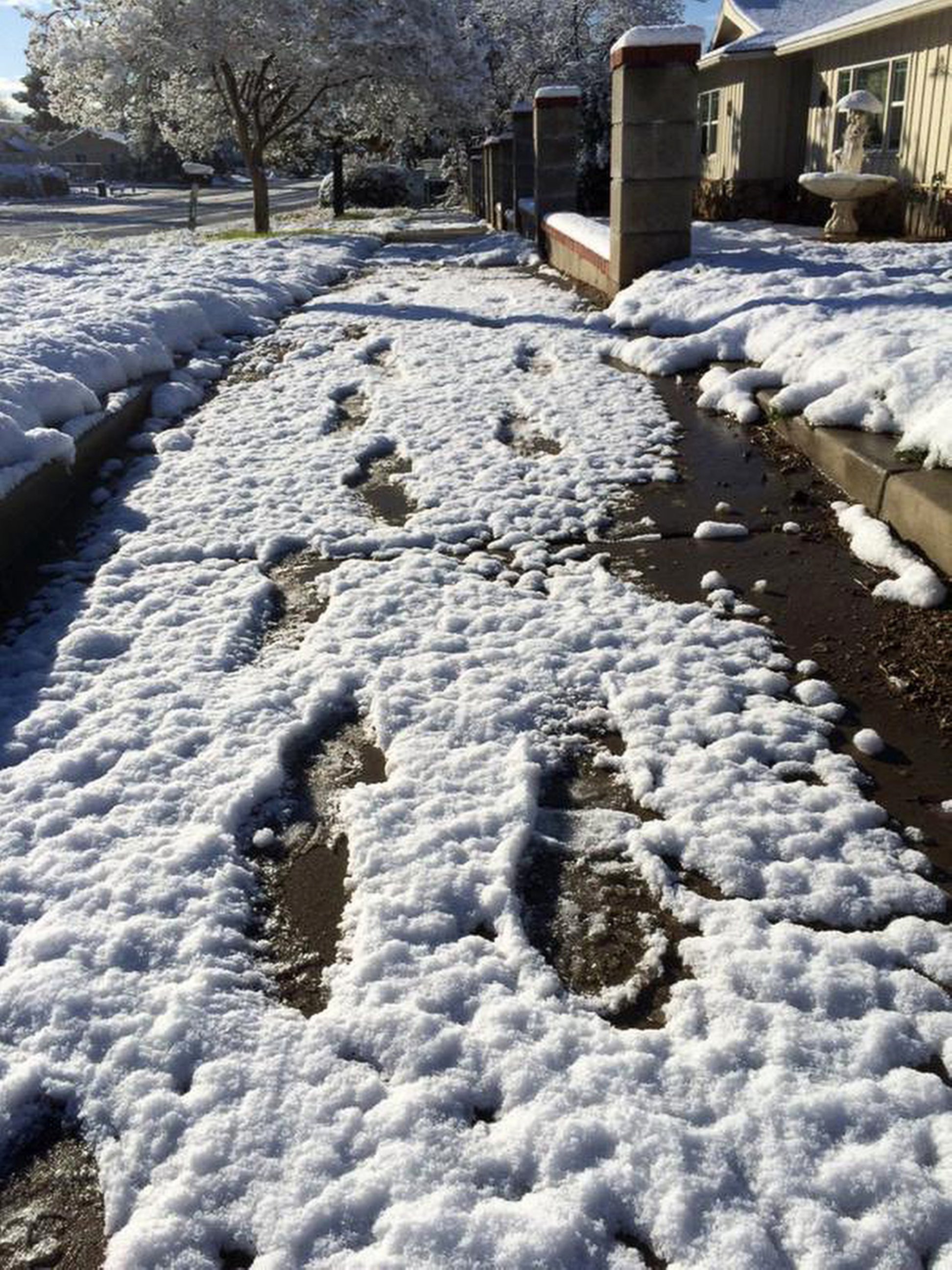 PHOTO: Footprints are left in the snow along a neighborhood street following last night's winter storm in Yucaipa, Calif., Dec. 31, 2014.