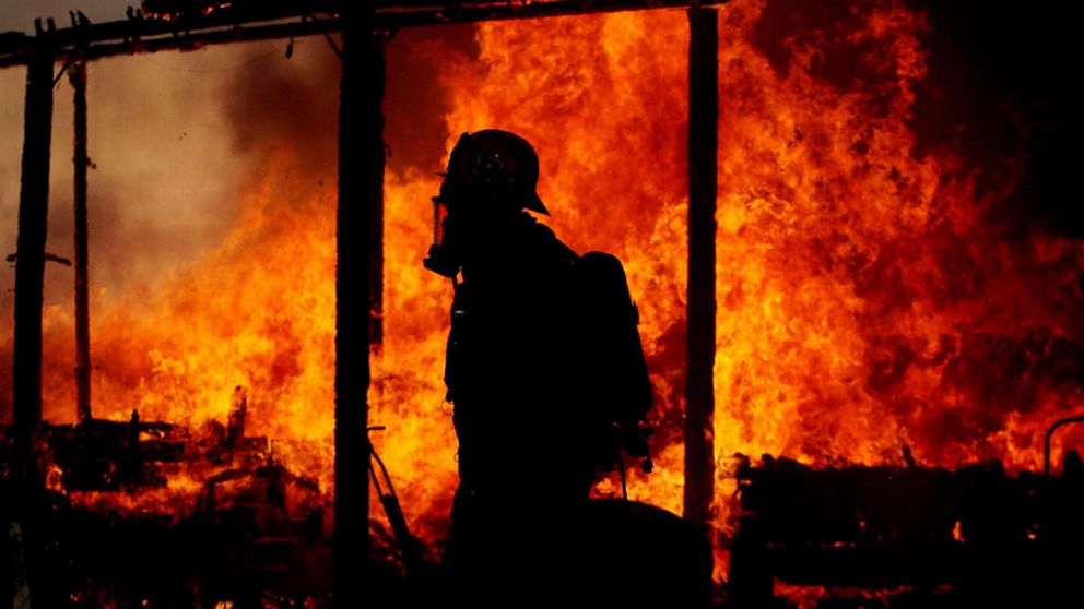 This Jan. 14, 2014 photo shows a Riverside County firefighter walking past a fully engulfed  burning home in Jurupa Valley, Calif. 