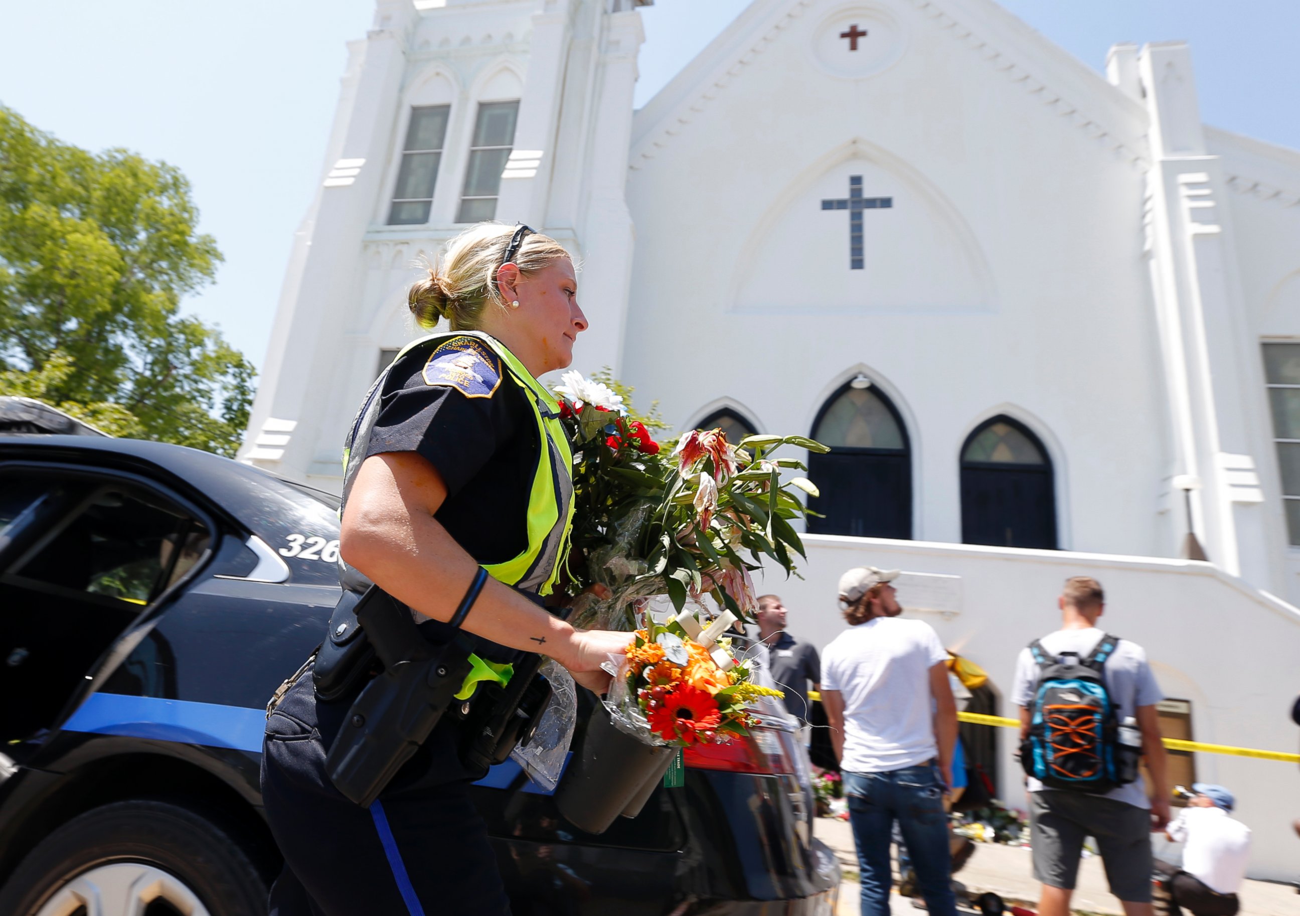 PHOTO: Charleston police officer T. Graves carries flowers, June 18, 2015 to a make-shift memorial in front of the Emanuel AME Church in Charleston, S.C.
