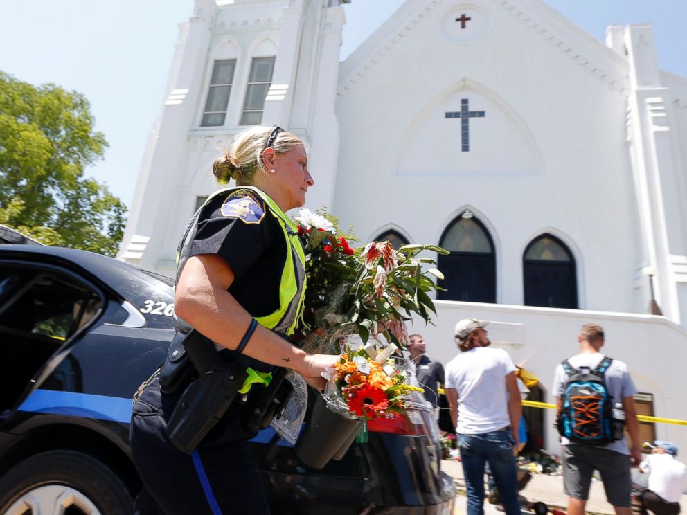 PHOTO: Charleston police officer T. Graves carries flowers, June 18, 2015 to a make-shift memorial in front of the Emanuel AME Church in Charleston, S.C.