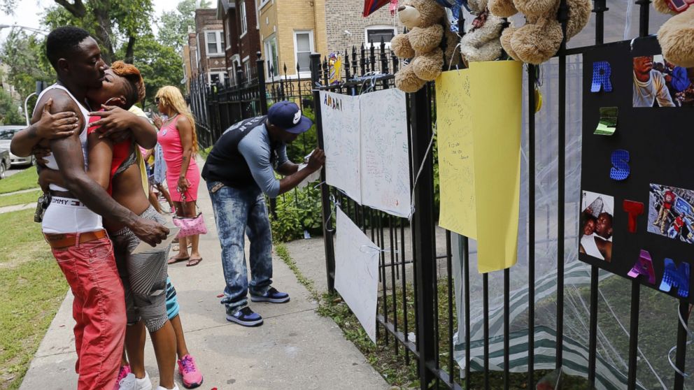 Antonio Brown, left, father of Amari Brown, is embraced by a community member, July 6, 2015, in Chicago. Authorities say 7-year-old Amari Brown, who was celebrating the Fourth of July with his family, was among three people who were shot and killed in Chicago. 