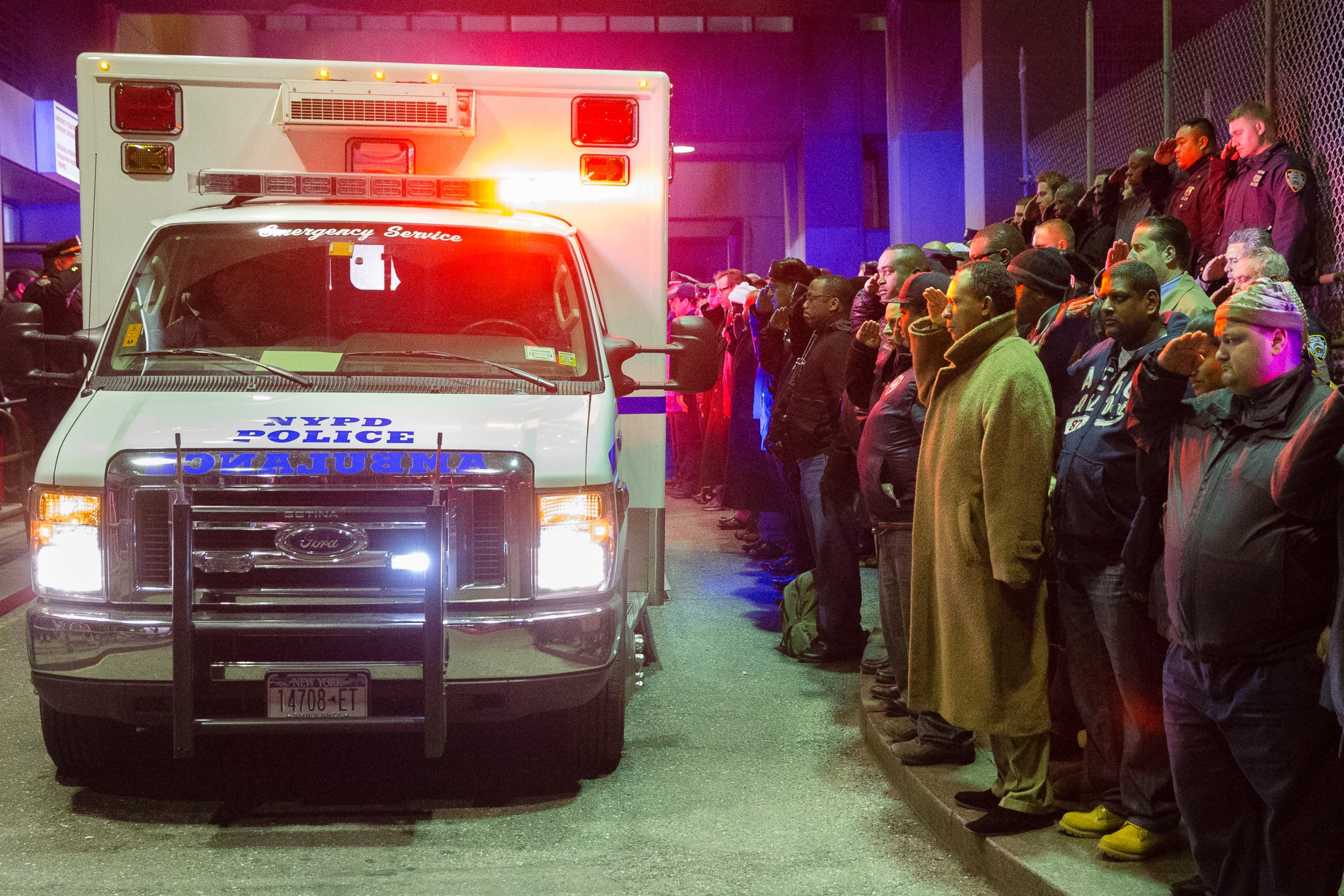 PHOTO: Mourners stand at attention as the bodies of two fallen NYPD police officers are transported from Woodhull Medical Center, Saturday, Dec. 20, 2014, in New York.