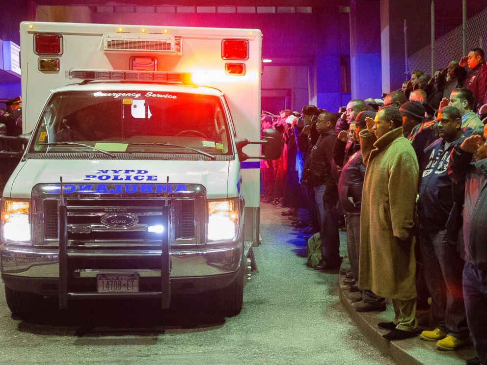 PHOTO: Mourners stand at attention as the bodies of two fallen NYPD police officers are transported from Woodhull Medical Center, Saturday, Dec. 20, 2014, in New York.