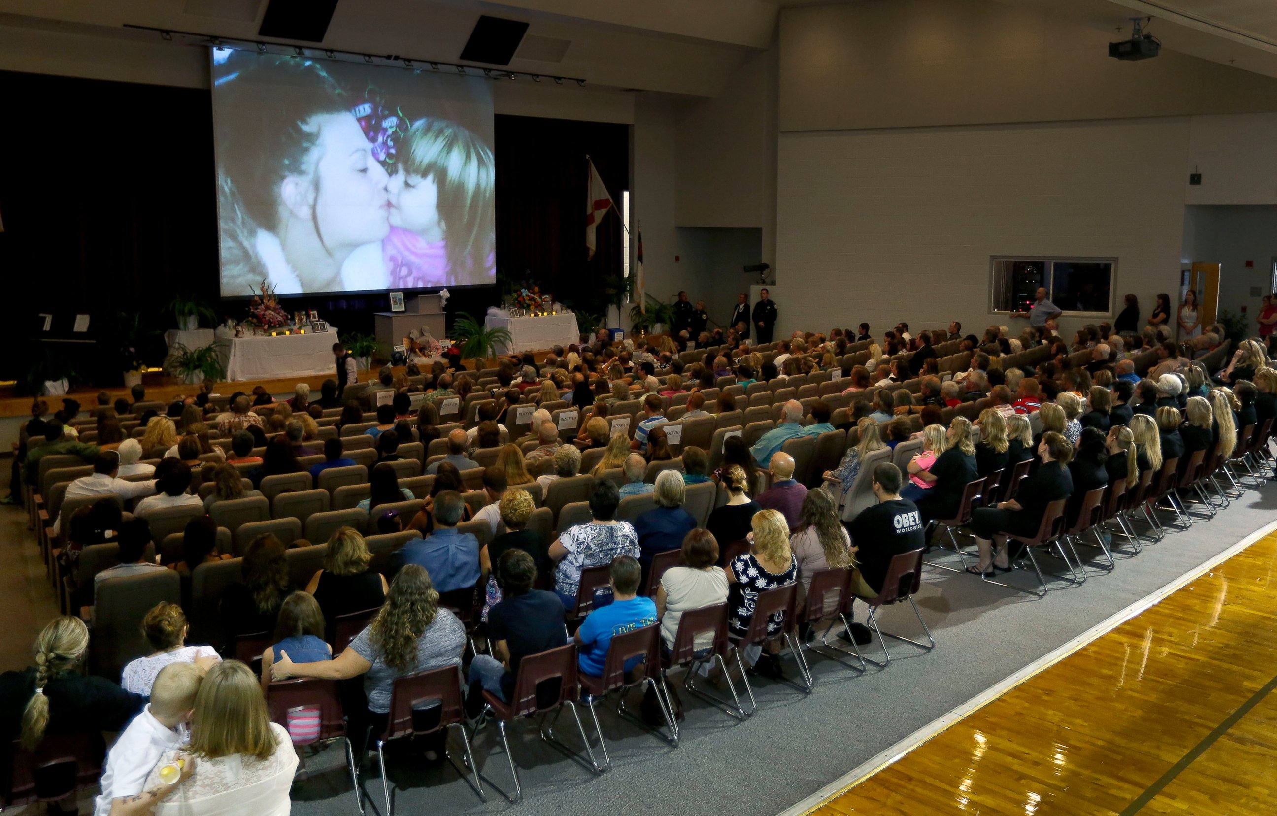PHOTO: Photos of Sarah Spirit and her children are displayed on the screen during a memorial service at Bell High School Don Spirit's family on Sept. 21, 2014, in Bell, Fla.